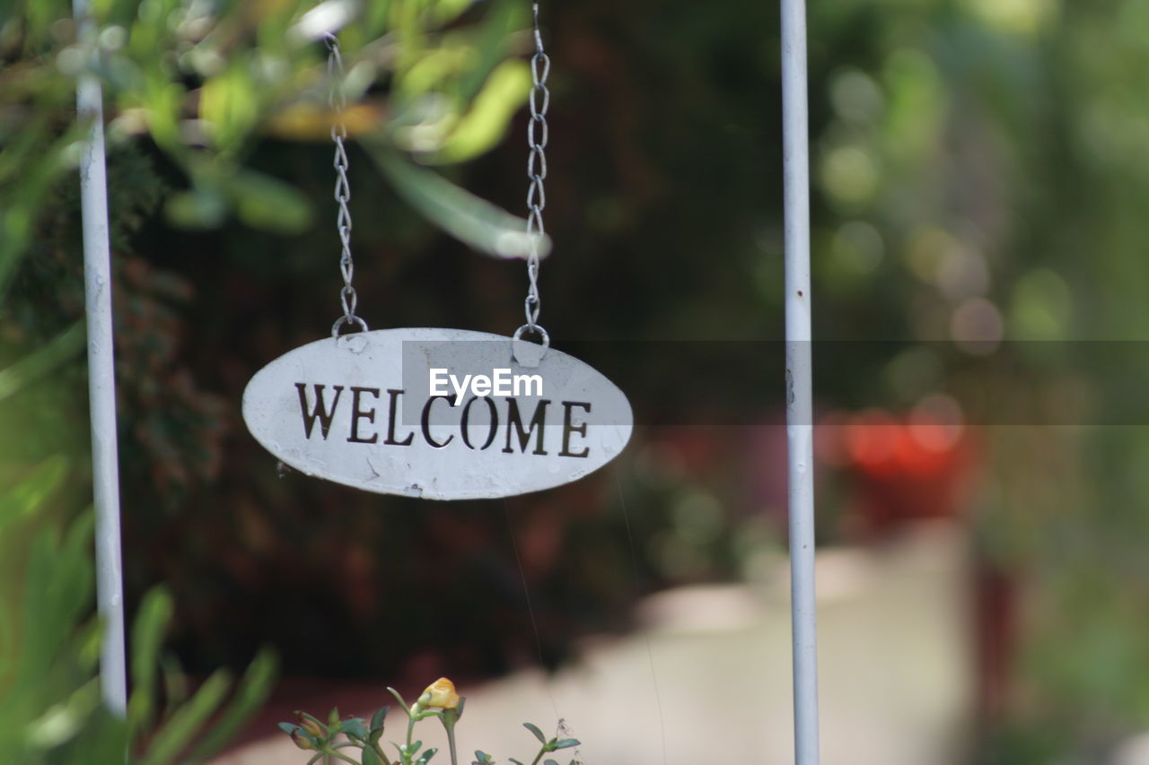 Close-up of welcome sign hanging outdoors