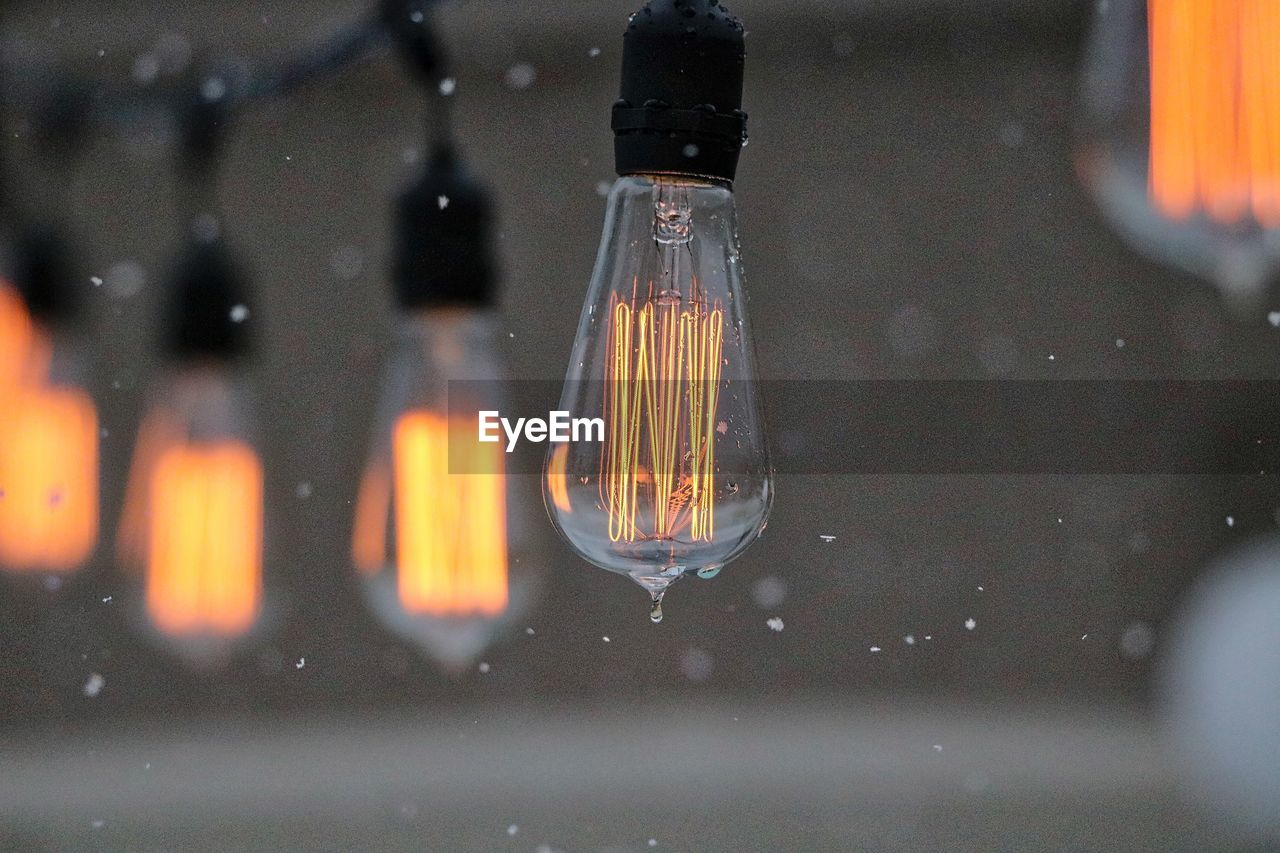 Illuminated light bulbs during snowfall