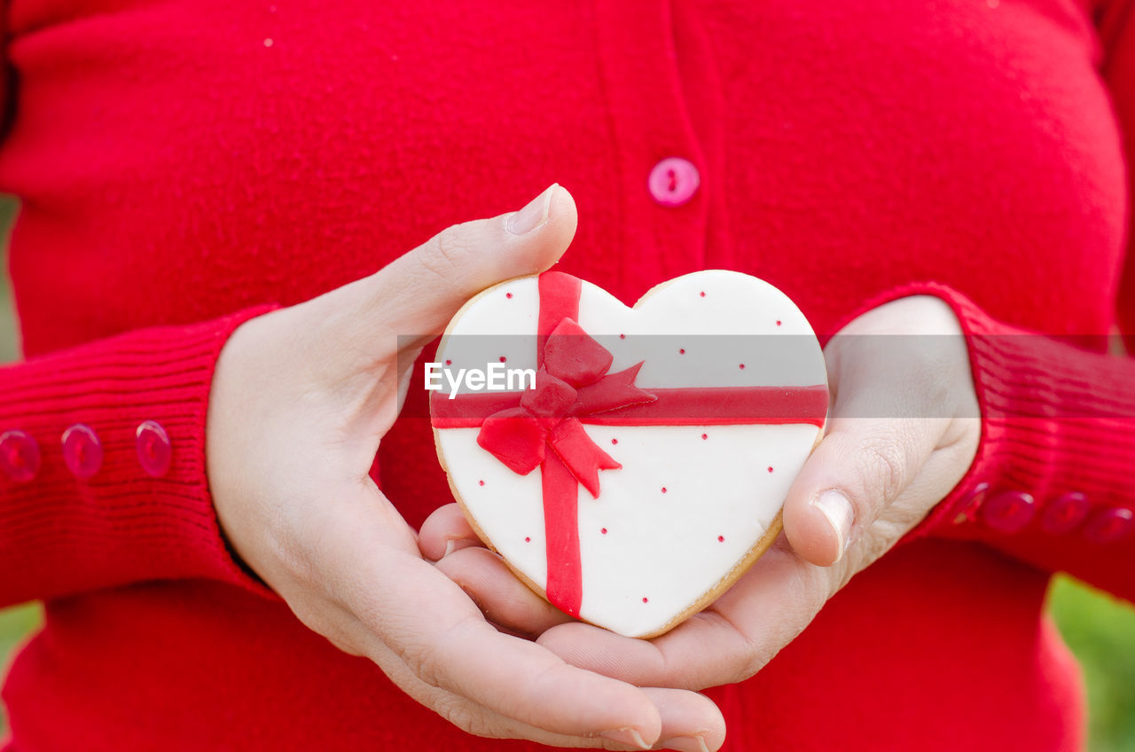 Close-up midsection of woman holding heart shaped cookie