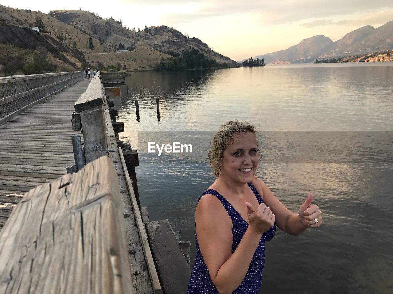 Portrait of smiling mature woman showing thumbs up by lake