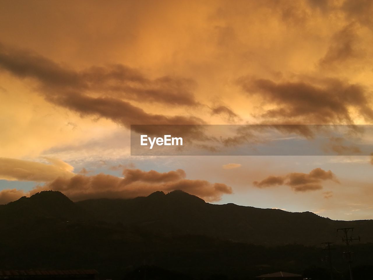 Scenic view of silhouette mountains against cloudy sky during sunset