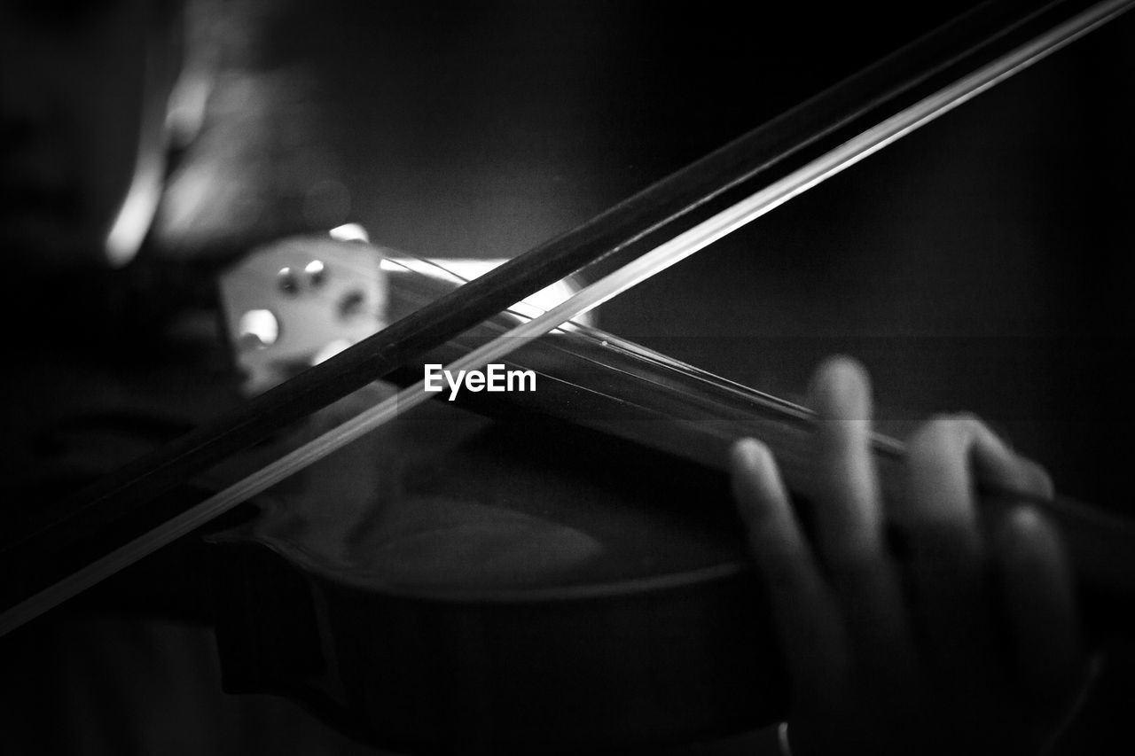 Cropped hand playing violin in darkroom