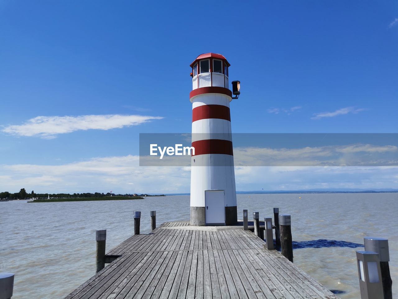 Lighthouse on pier by sea against sky