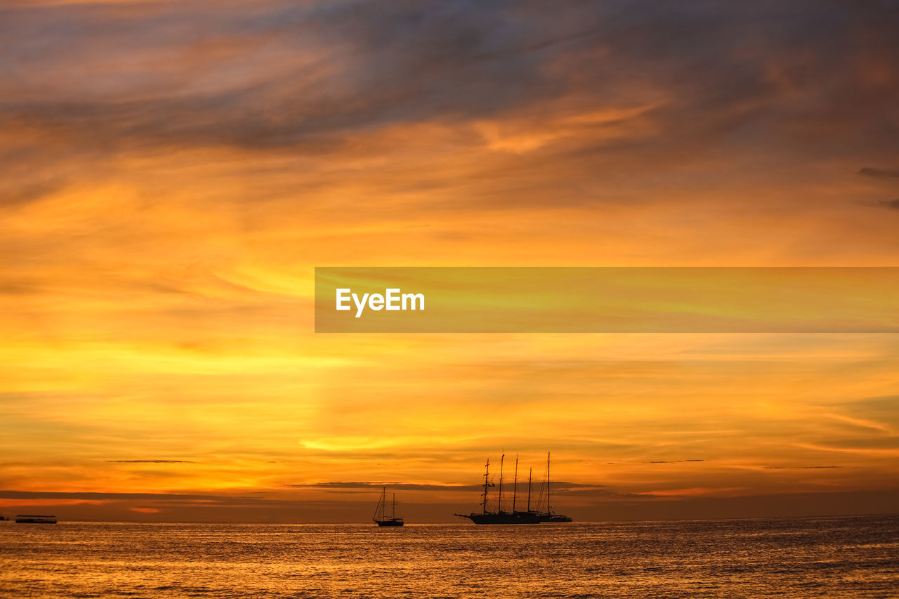 Scenic view of sea against dramatic sky during sunset