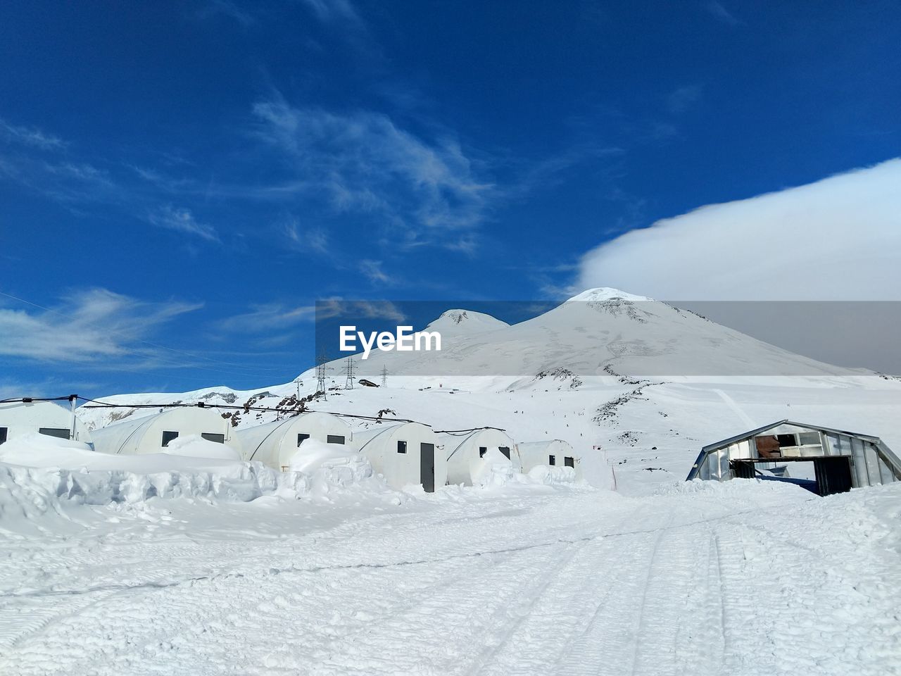 Scenic view of snow covered mountains against blue sky