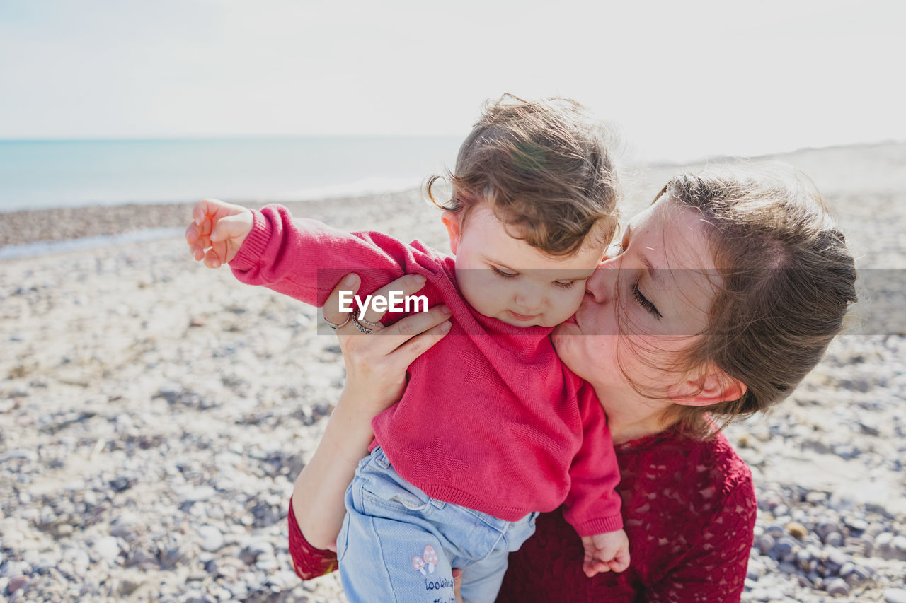 Mother kissing daughter at beach