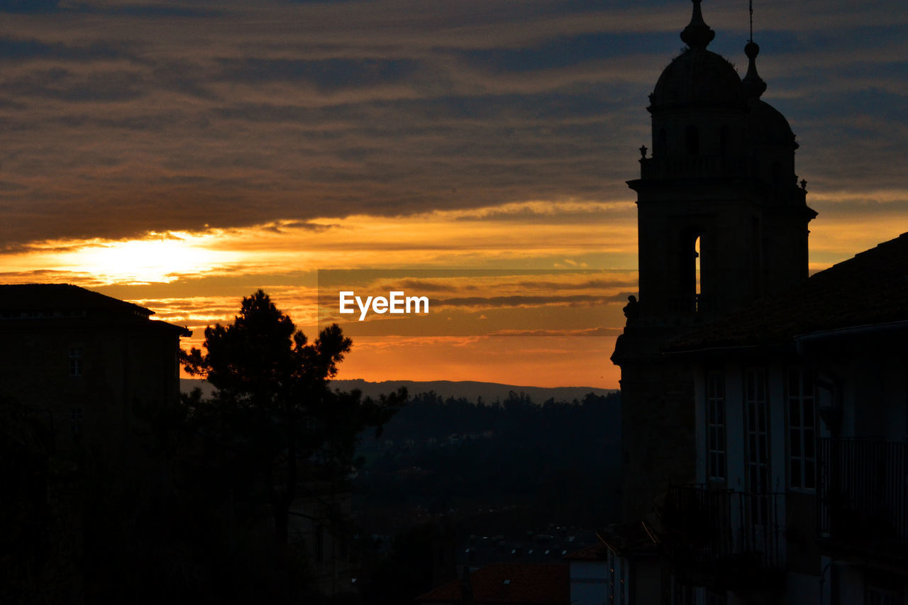 SILHOUETTE TOWER AND TREES AGAINST SKY AT SUNSET