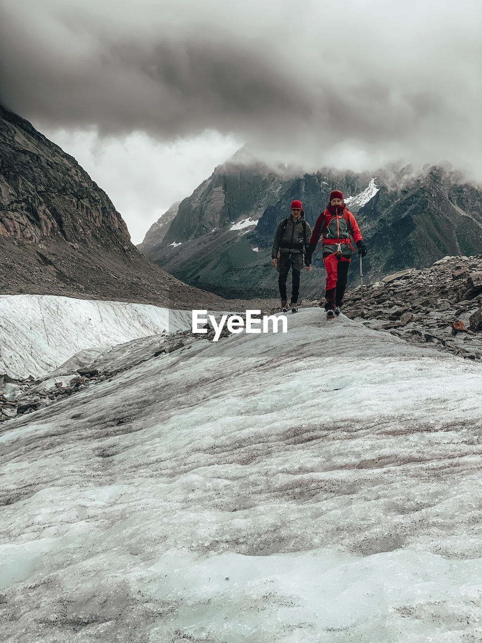 Two mountaineers descending glacier in france under dramatic clouds