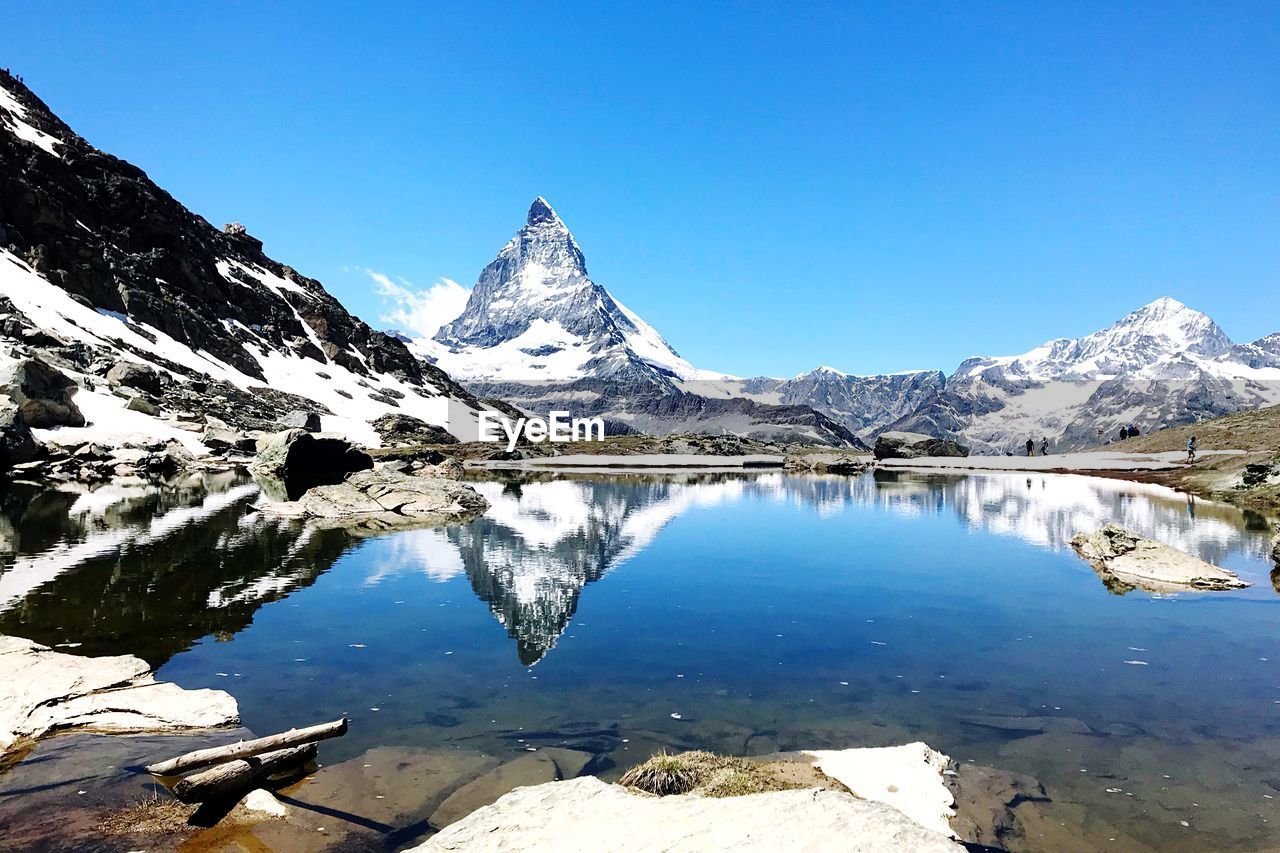 Scenic view of lake by snowcapped mountains against sky