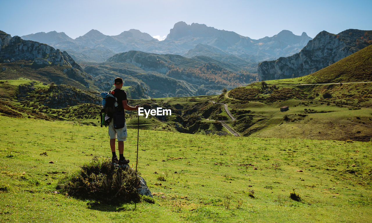 Full length of man with backpack looking at mountains during sunny day