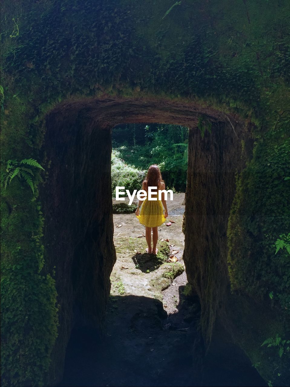 Rear view of woman standing on rock seen through archway