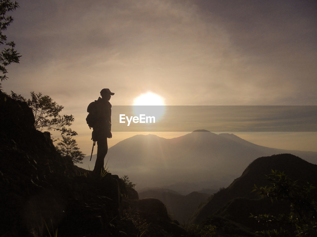 Man standing on mountain against sky during sunset