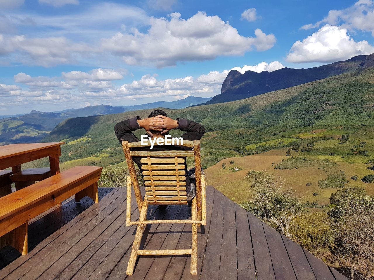 Rear view of man sitting on chair against mountains