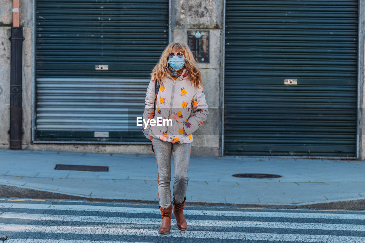 Portrait of woman wearing mask standing against building