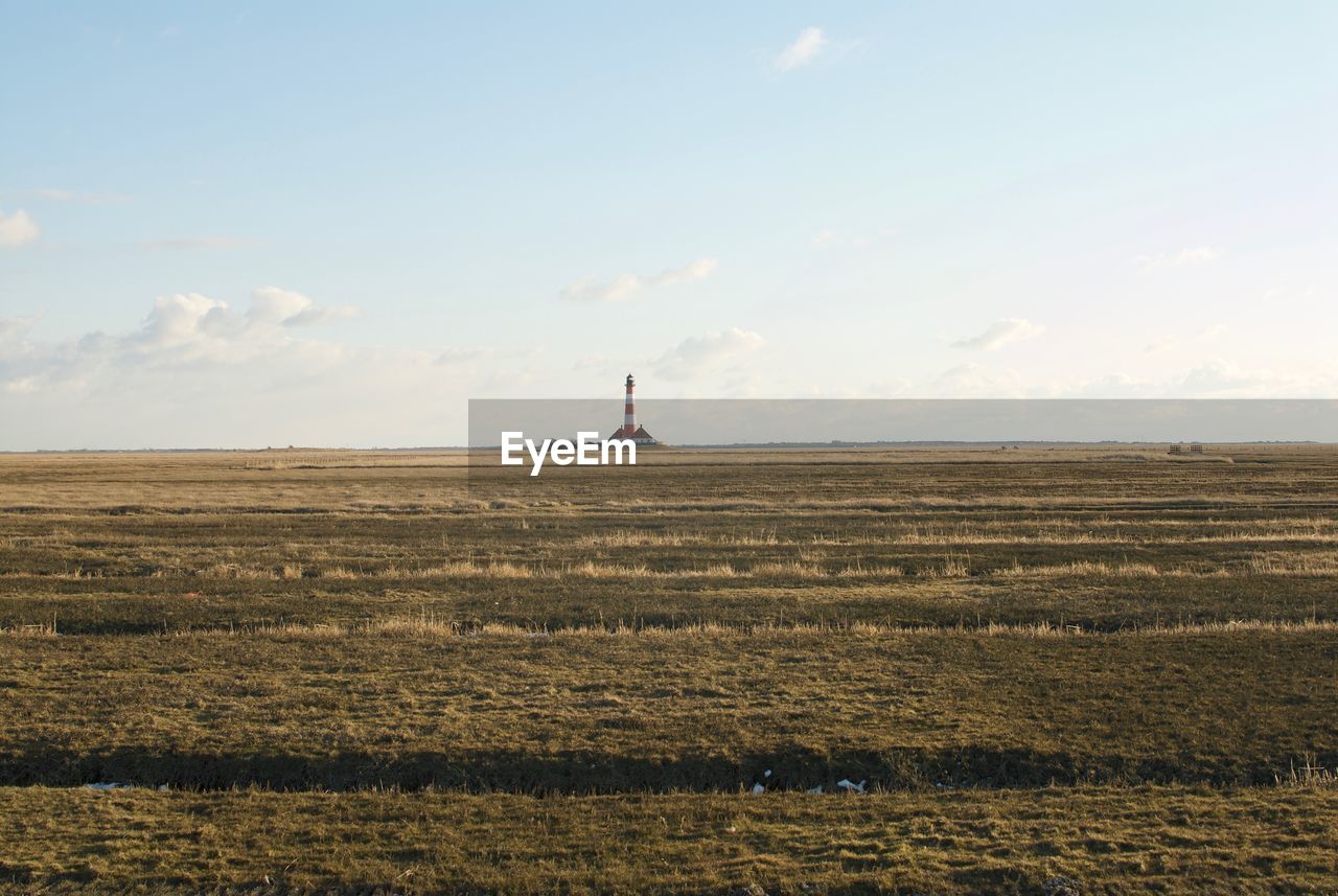 Lighthouse on field against sky