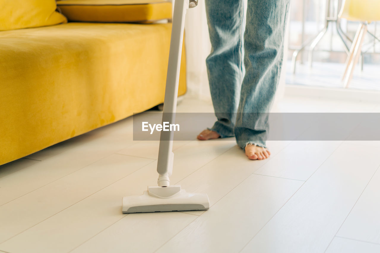 An unrecognizable person is vacuuming the floor in the room.