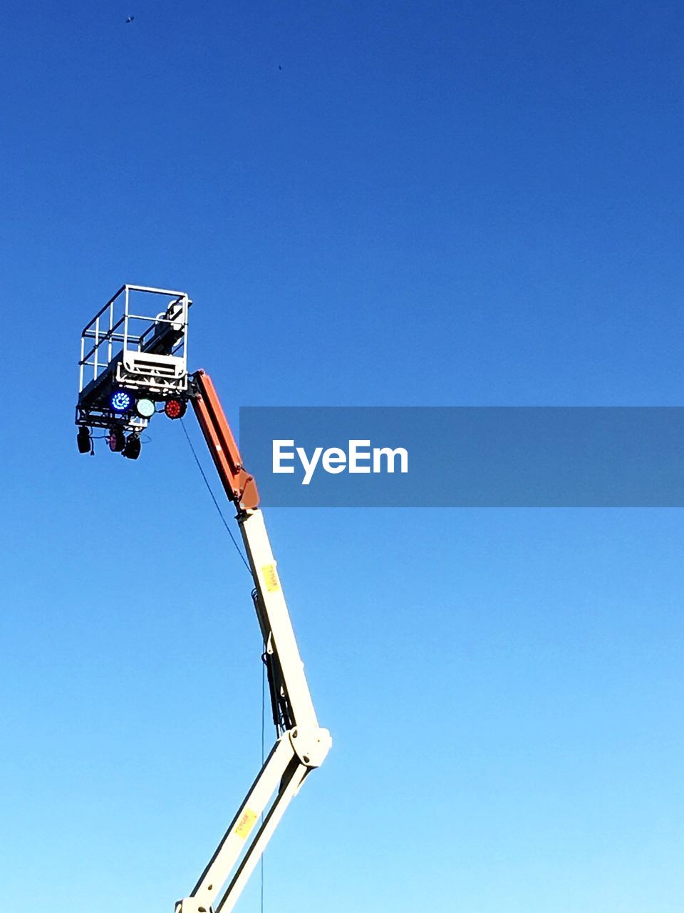 Low angle view of cherry picker against clear blue sky