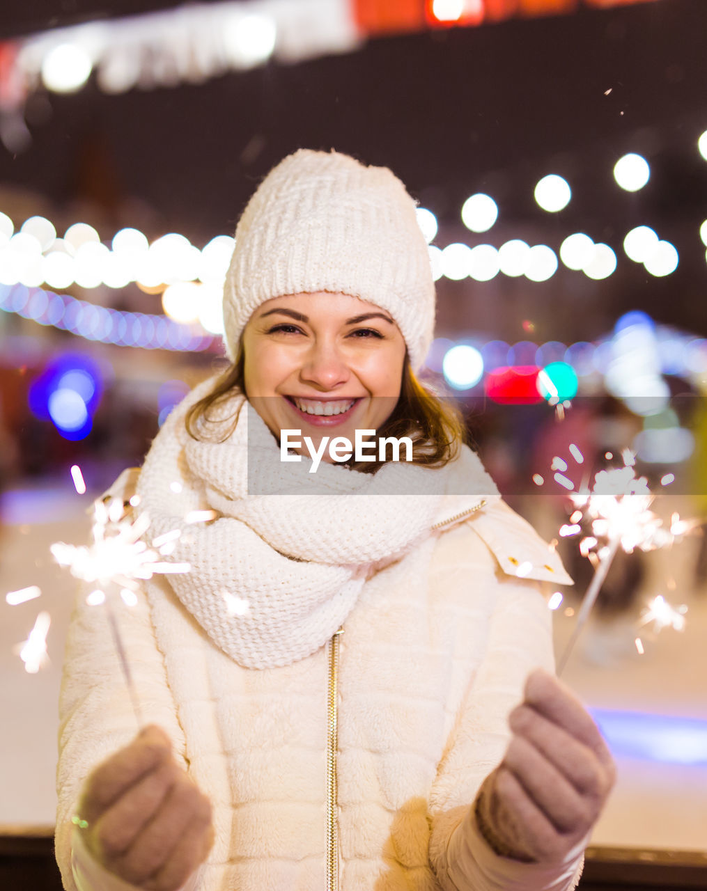 portrait of young woman standing against illuminated christmas tree at night