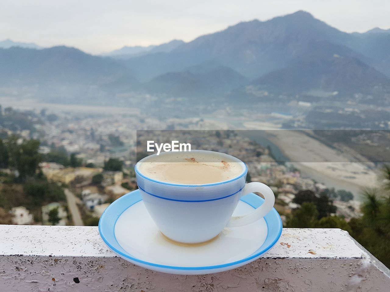 Close-up of coffee cup on railing against mountains
