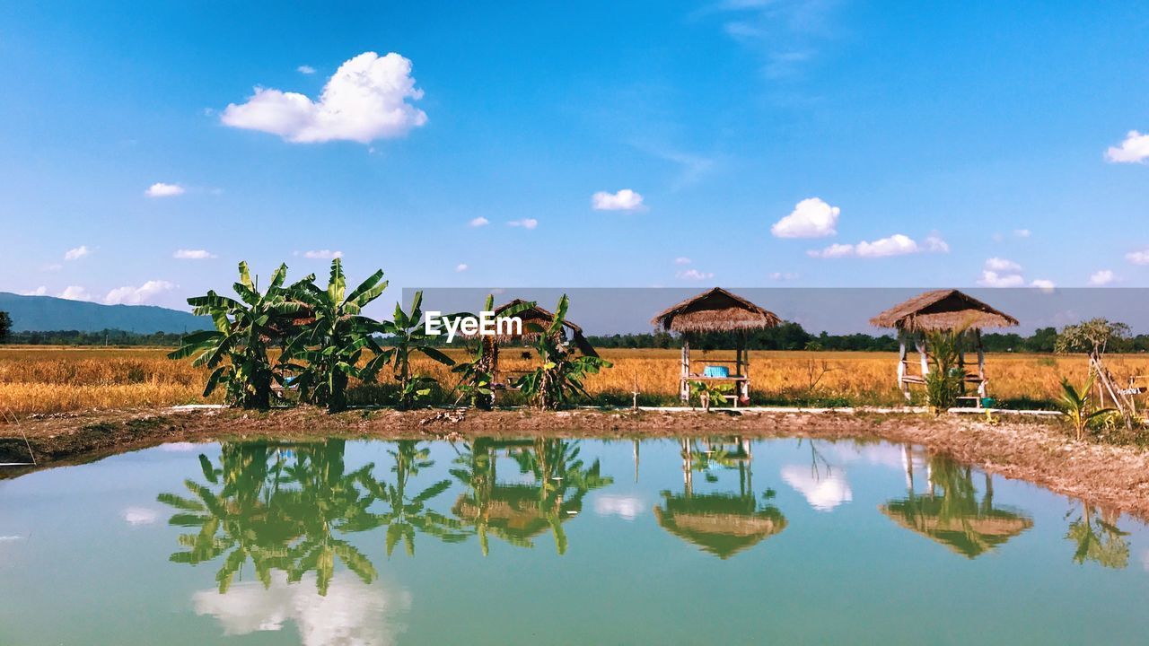 Reflection of building and trees in lake against sky