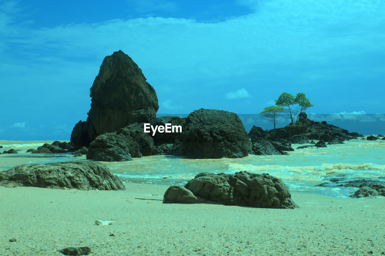 ROCKS ON BEACH AGAINST SKY