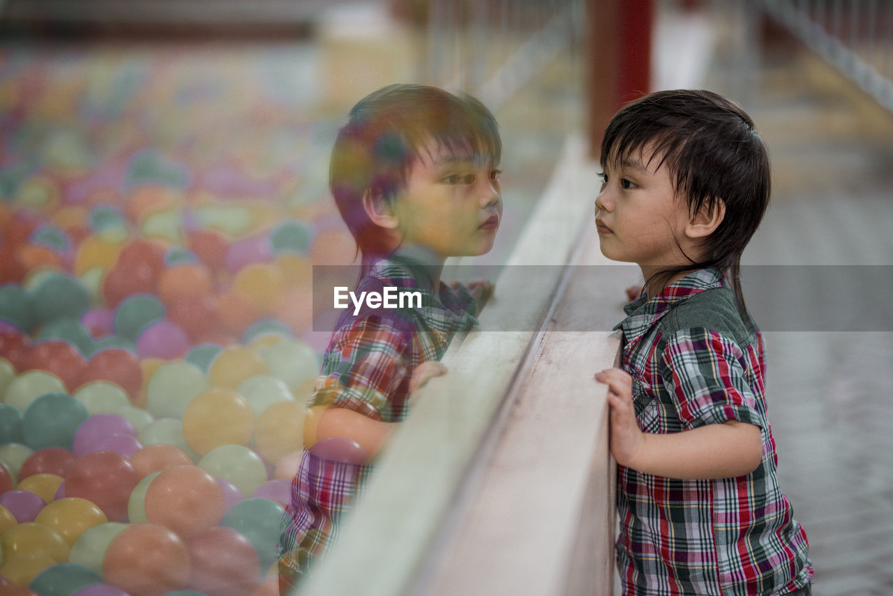 Side view of cute boy looking at multi colored balls