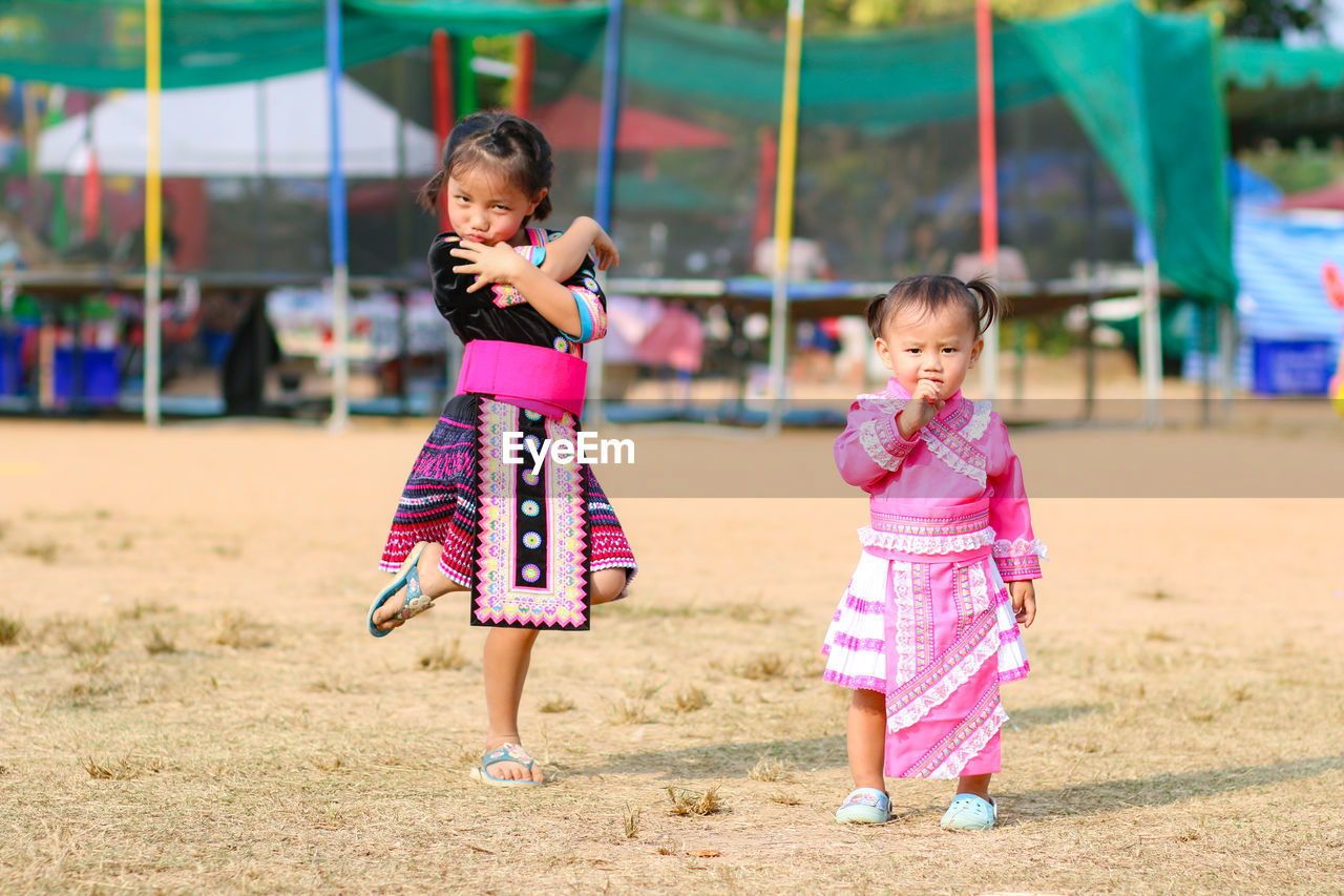 Portrait of cute sisters standing on land