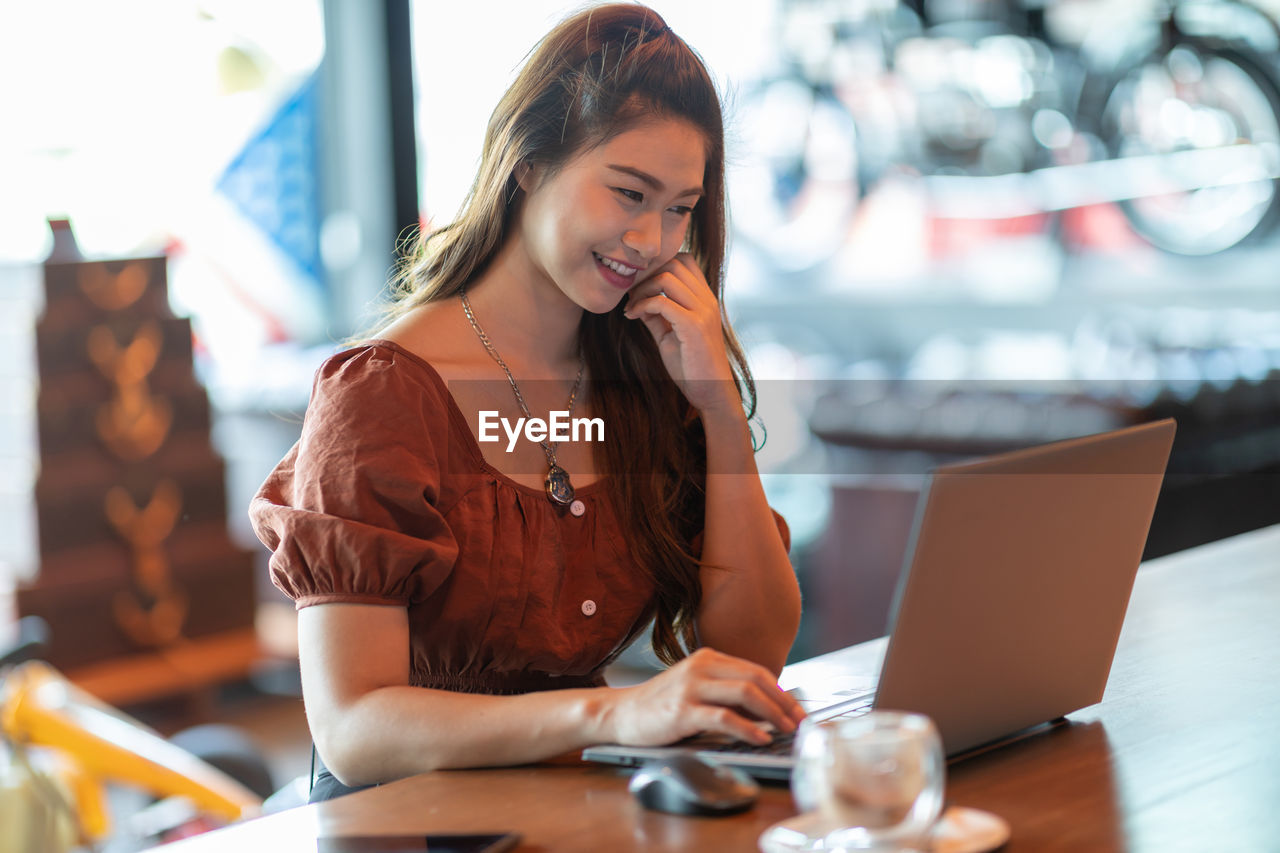 Woman using laptop while sitting at table in cafe