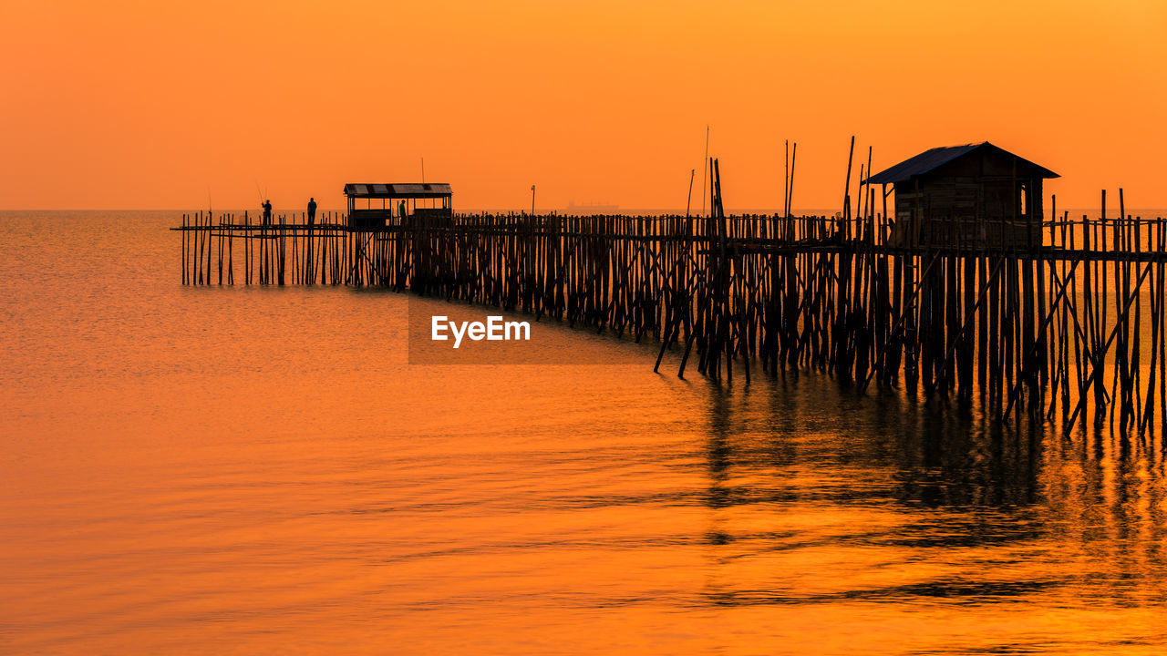 PIER OVER SEA AGAINST ORANGE SKY