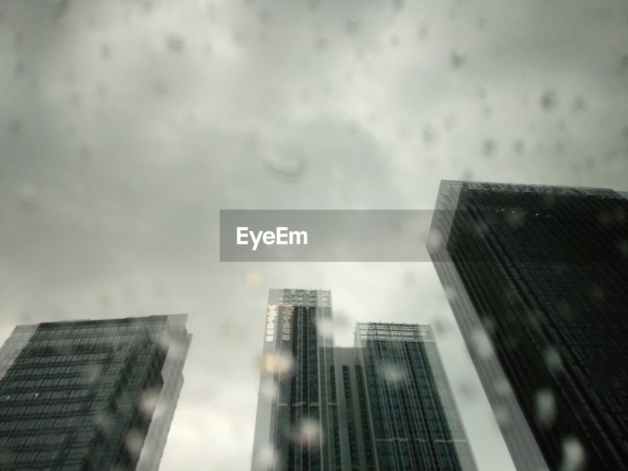 LOW ANGLE VIEW OF MODERN BUILDINGS IN CITY DURING RAINY SEASON