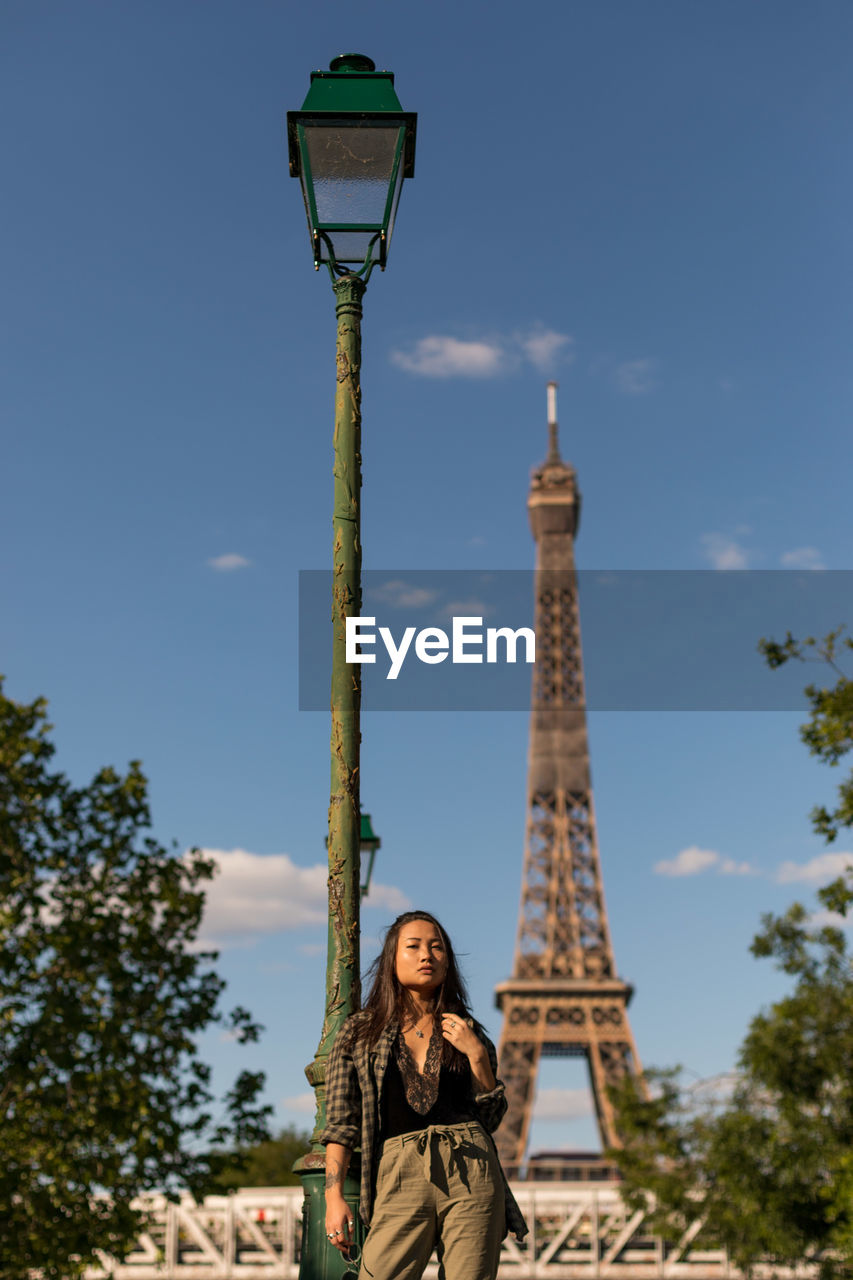 Low angle view of woman standing against eiffel tower