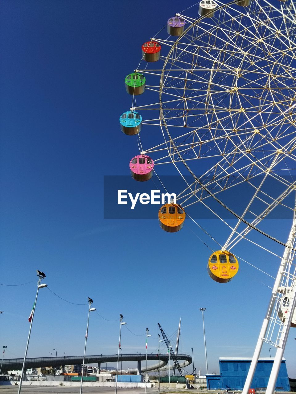 Low angle view of ferris wheel against clear blue sky