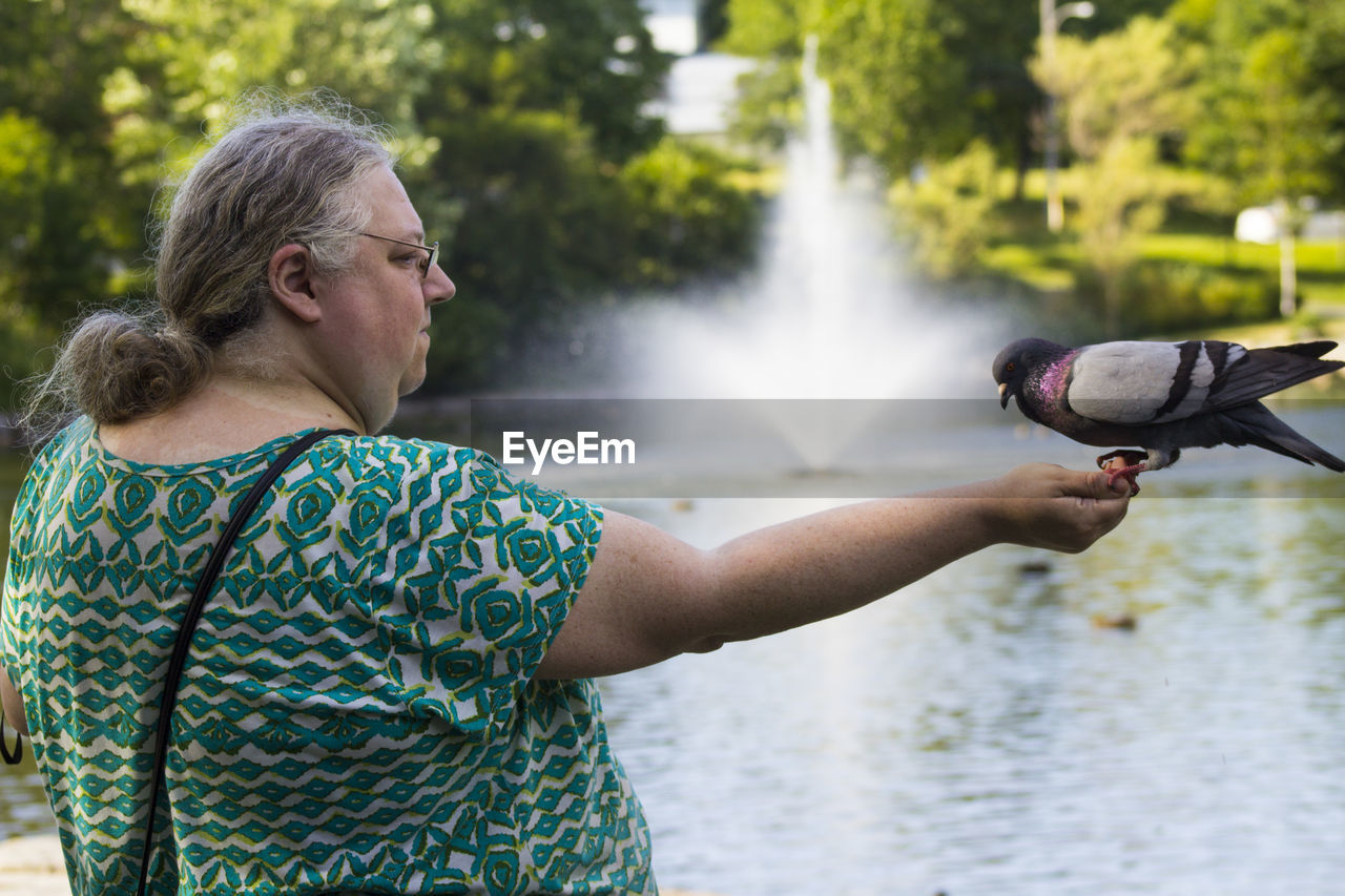 Woman with pigeon by lake