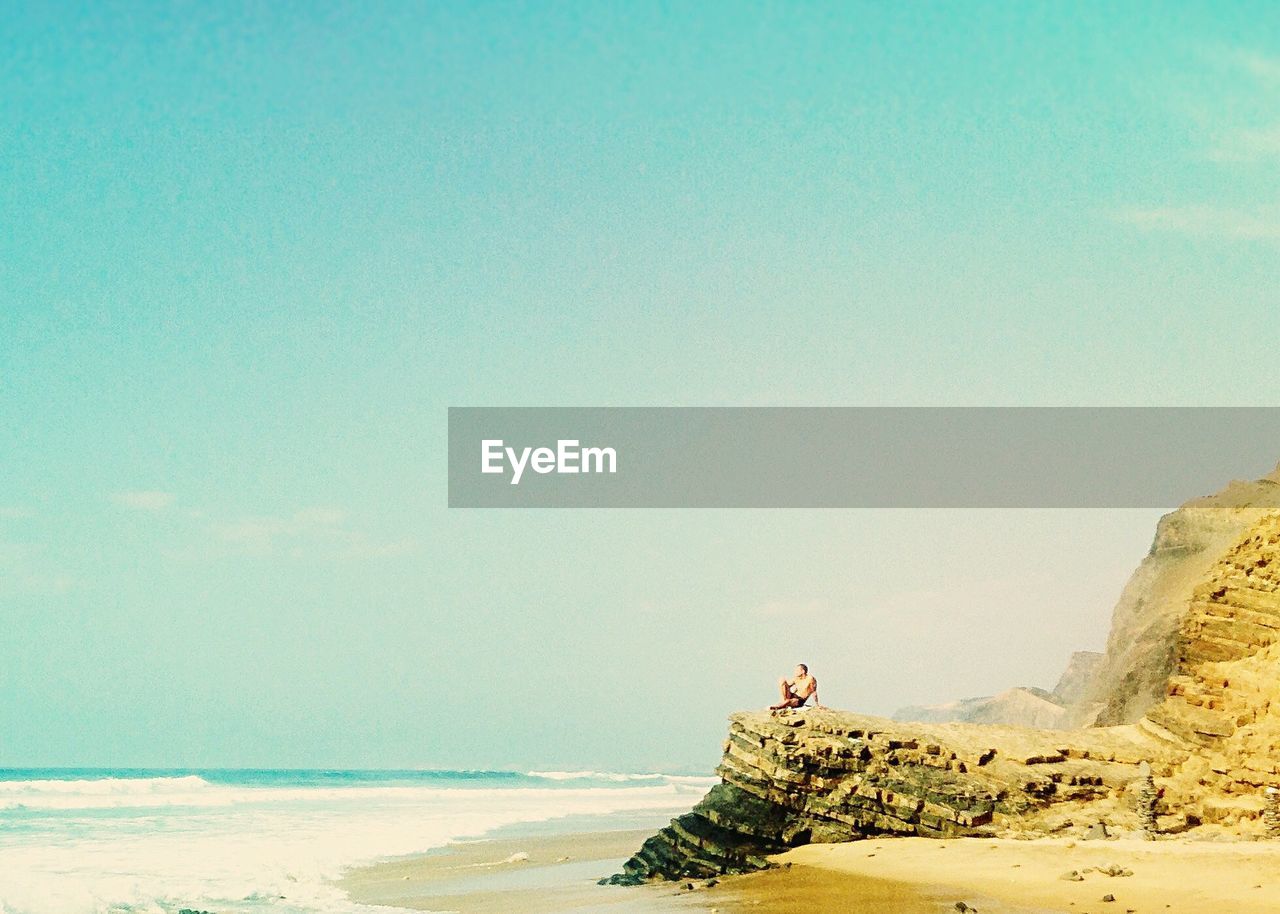 Man on beach against clear blue sky