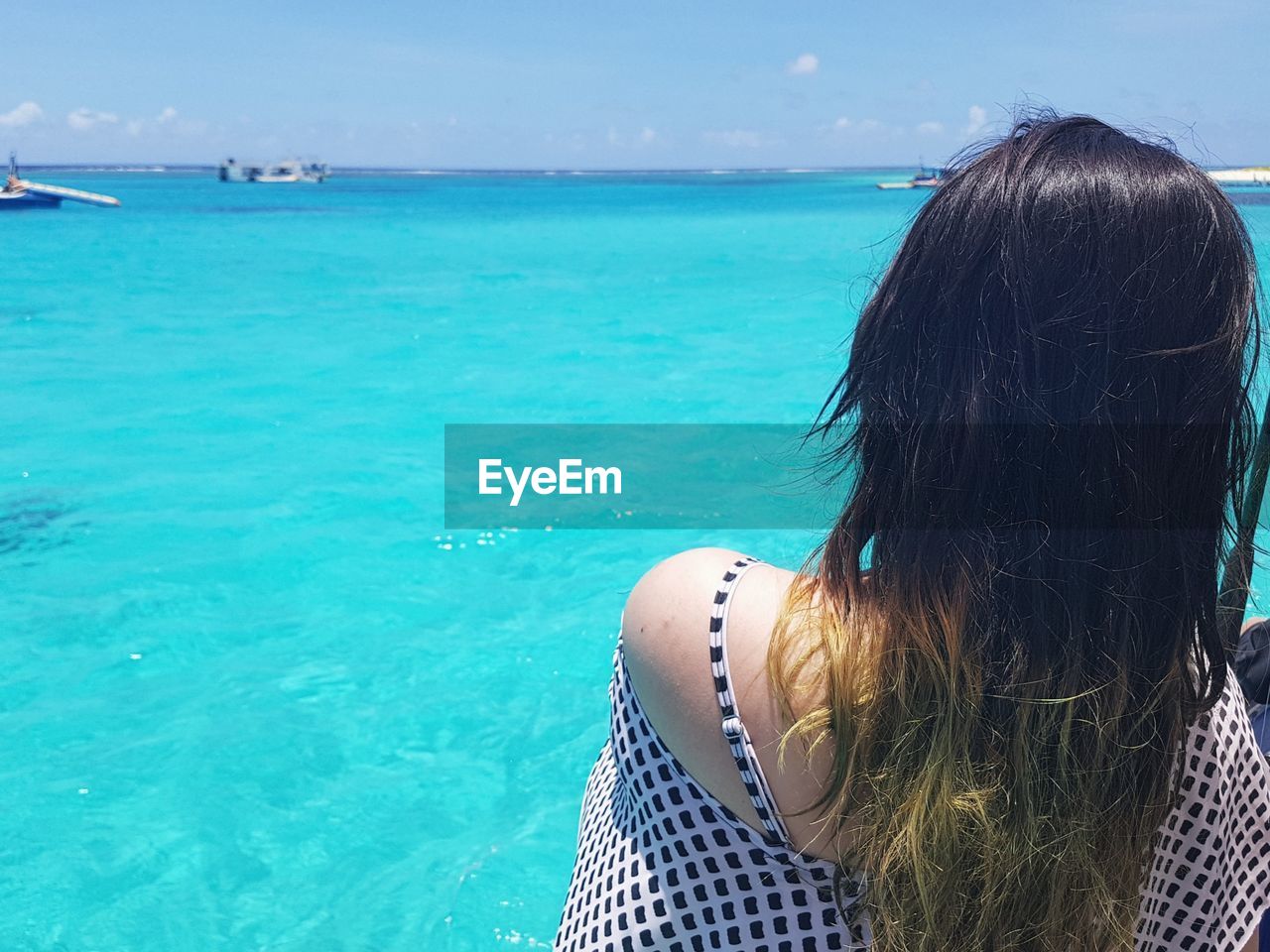 Rear view of woman standing by sea against blue sky