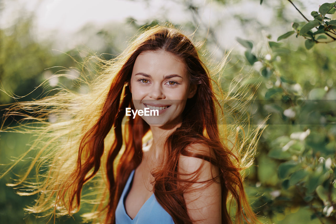 portrait of smiling young woman standing against plants