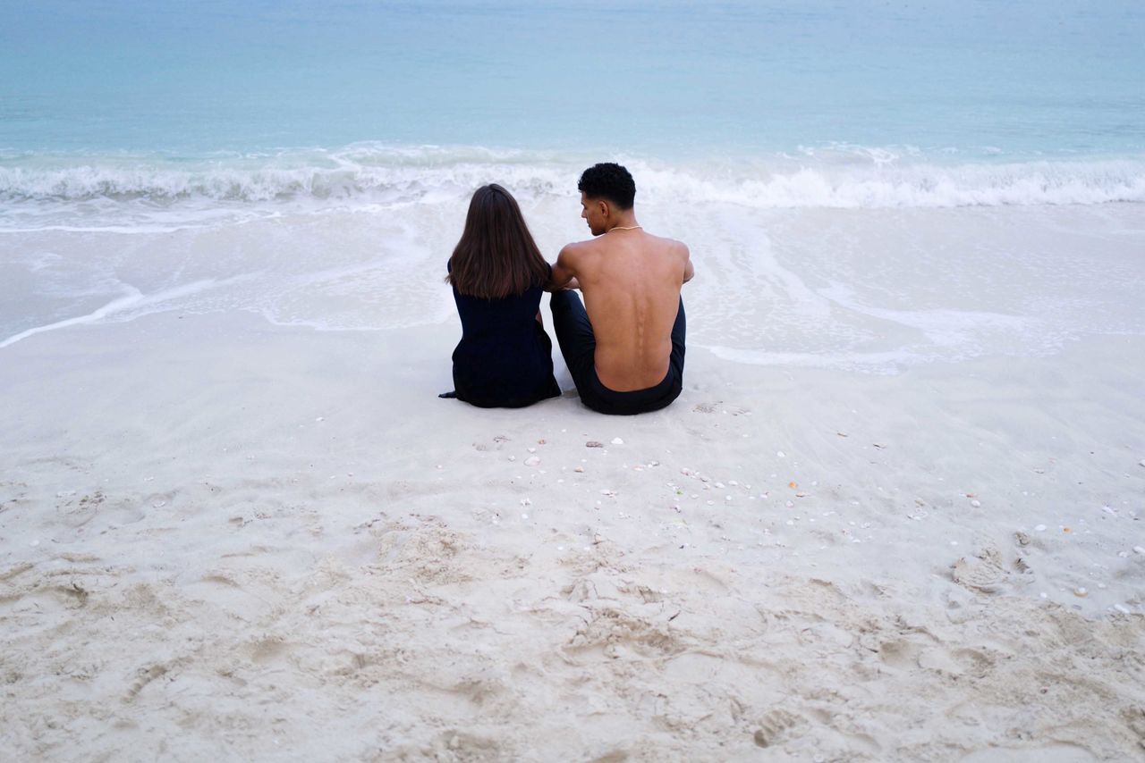 Portrait of young couple sitting in the beach together 