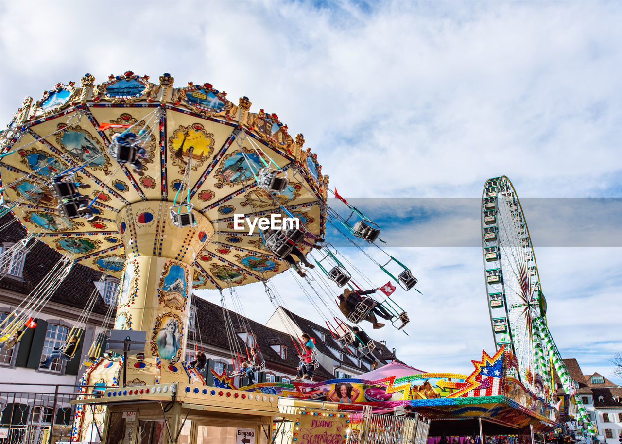 Low angle view of ferris wheel against cloudy sky