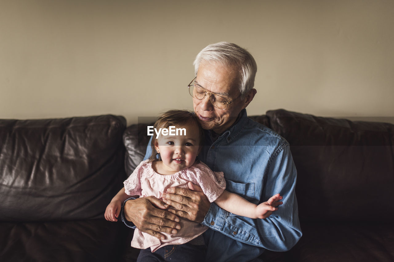 Portrait of grandfather holding toddler and looking at her