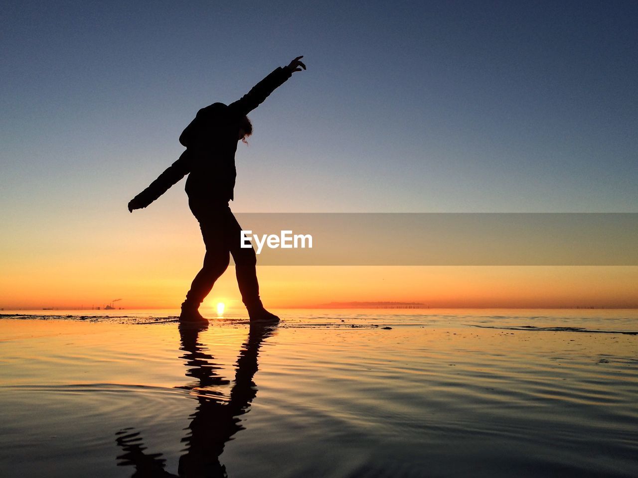 Silhouette man standing on beach against sky during sunset