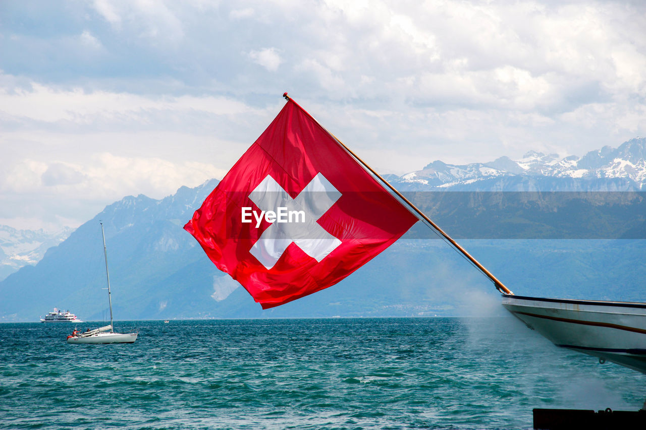 Red flag on lake against sky