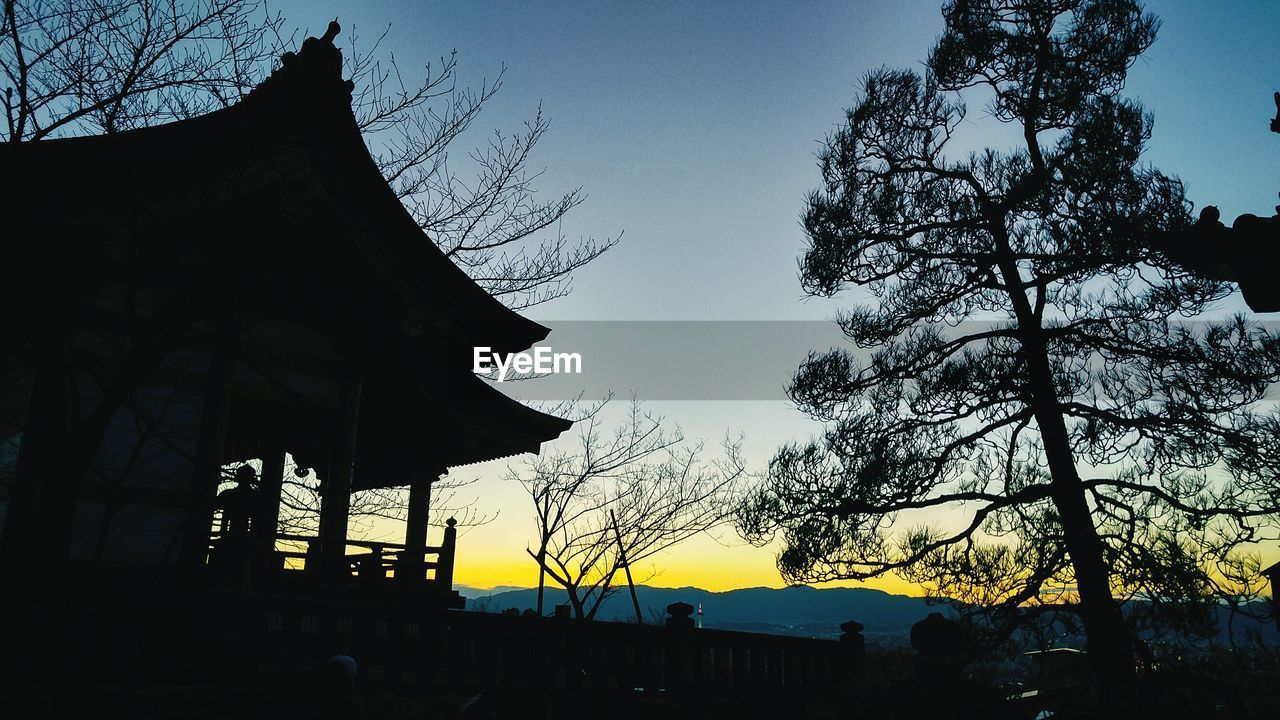 Low angle view of silhouette gazebo and trees against sky during sunset