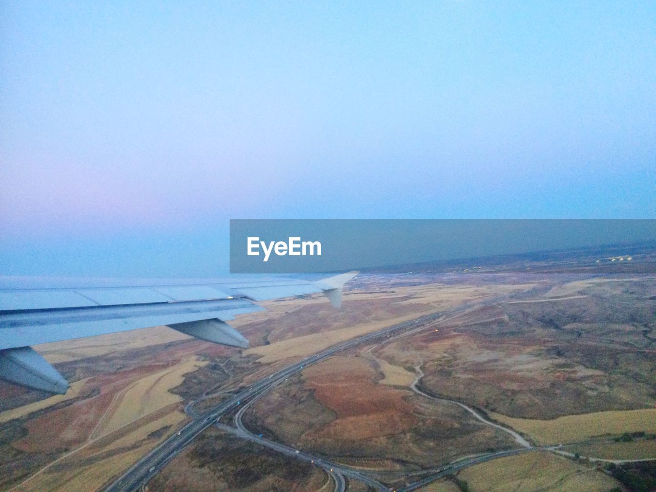 Cropped image of airplane wing flying over landscape in sky