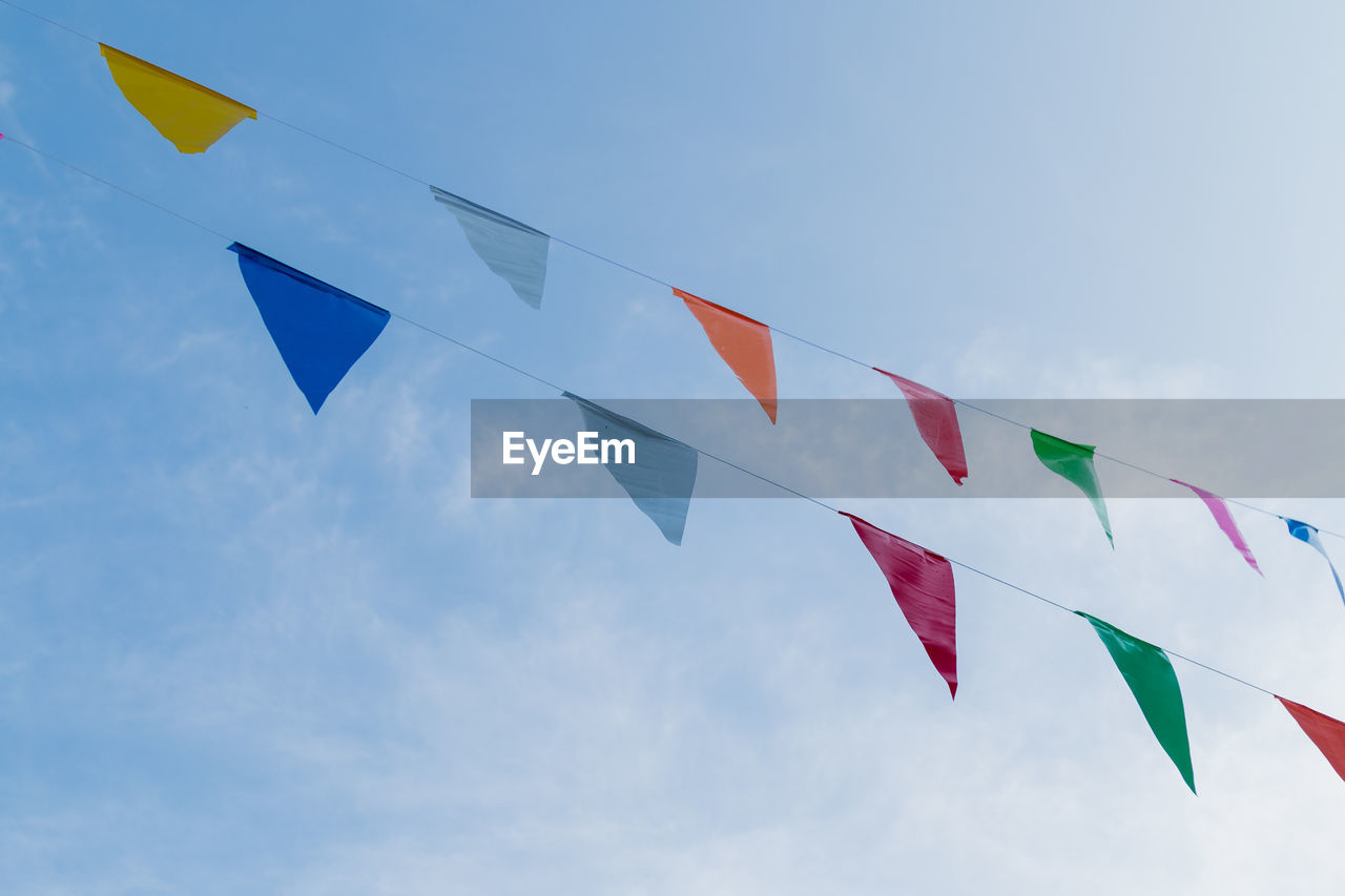 LOW ANGLE VIEW OF FLAGS HANGING AGAINST SKY