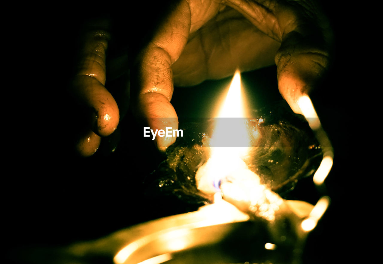 Close-up of person hands lighting diya