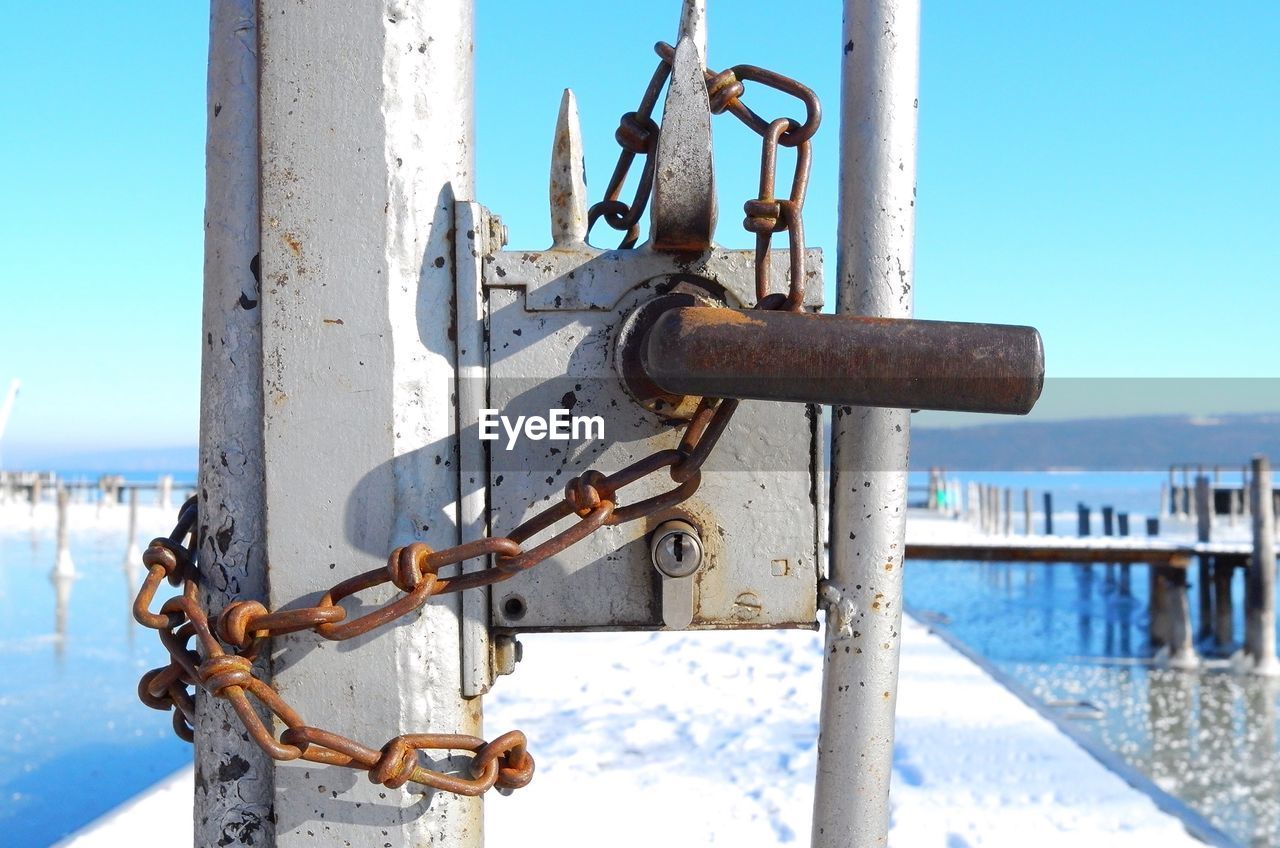 Close-up of padlocks on sea against clear sky