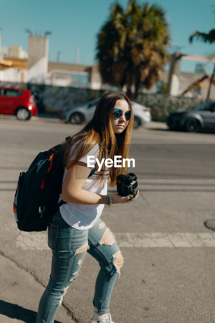 YOUNG WOMAN WEARING SUNGLASSES ON STREET AT CITY