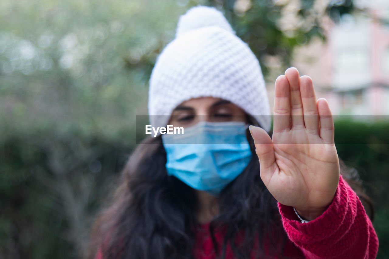 Young latin woman with medical mask making stop or denial sign