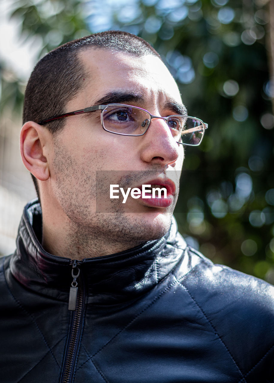 Close-up of young man wearing eyeglasses looking away