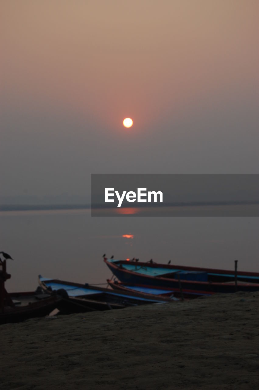 BOATS MOORED ON SEA AGAINST SKY AT SUNSET